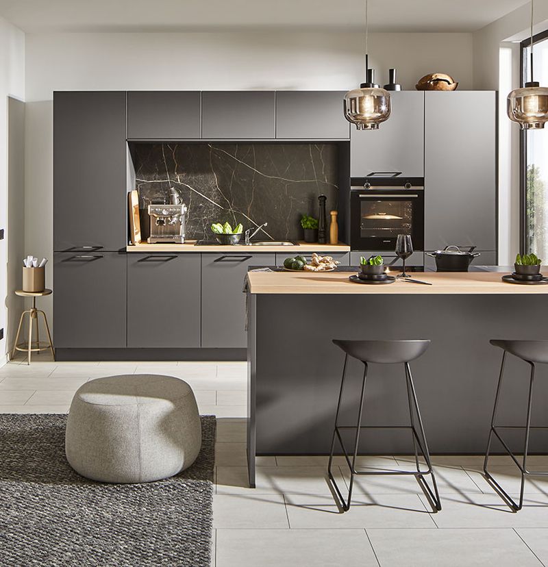 Schwarze Designküche mit Kochtresen und heller Holzarbeitsplatte