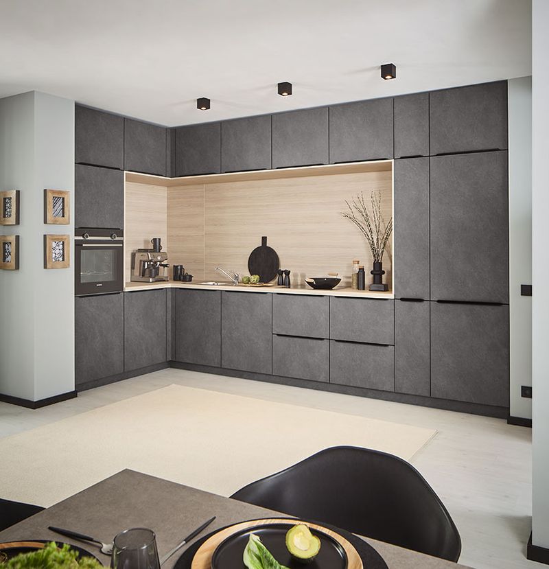 Klassische L-Küche in Grau-Granitoptik mit heller Holzarbeitsplatte und Nischenrückwand