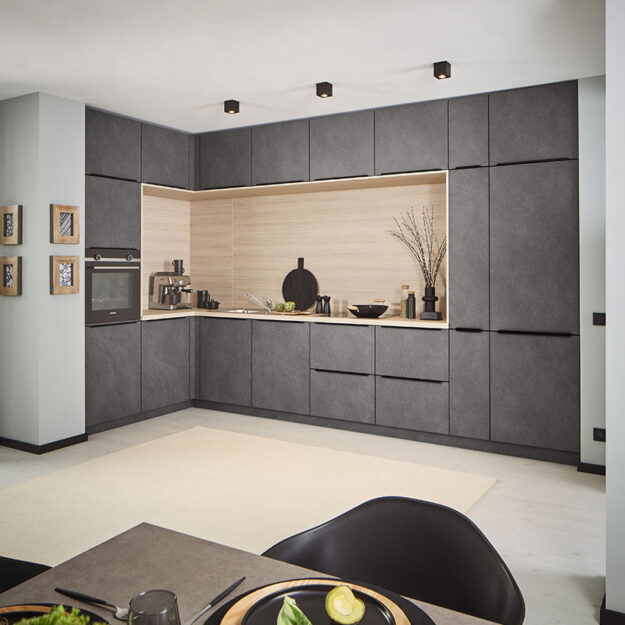 Klassische L-Küche in Grau-Granitoptik mit heller Holzarbeitsplatte und Nischenrückwand.