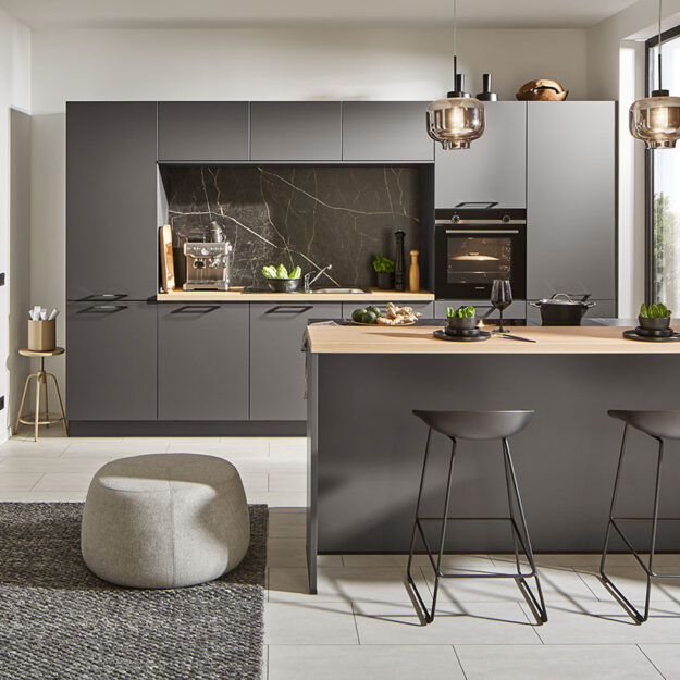 Küchen Meinersen – Schwarze Designküche mit Kochtresen und heller Holzarbeitsplatte.