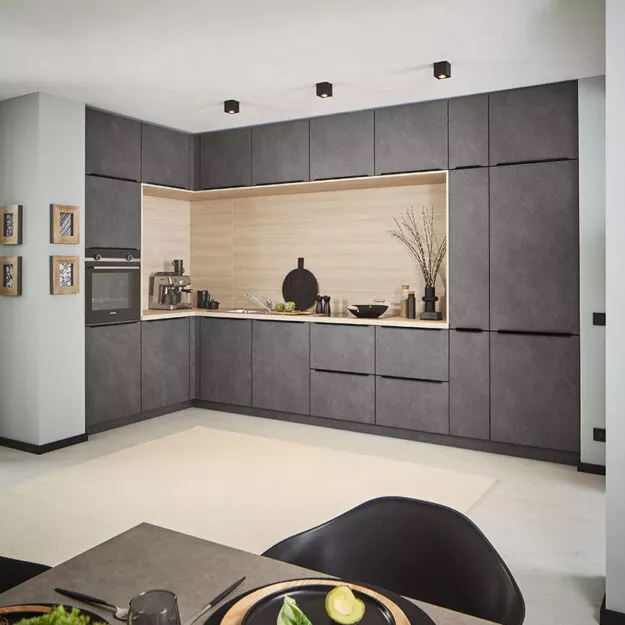 Klassische L-Küche in Grau-Granitoptik mit heller Holzarbeitsplatte und Nischenrückwand.