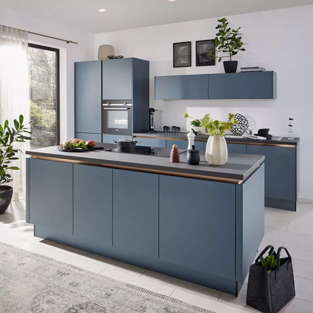 Blaue, moderne Küche mit Kochtresen und bronzefarbenen Kehlleisten.