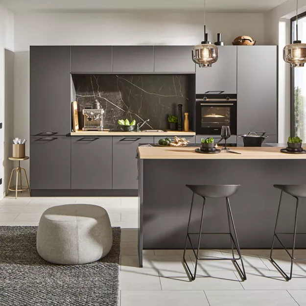 Küchen Meinersen – Schwarze Designküche mit Kochtresen und heller Holzarbeitsplatte.